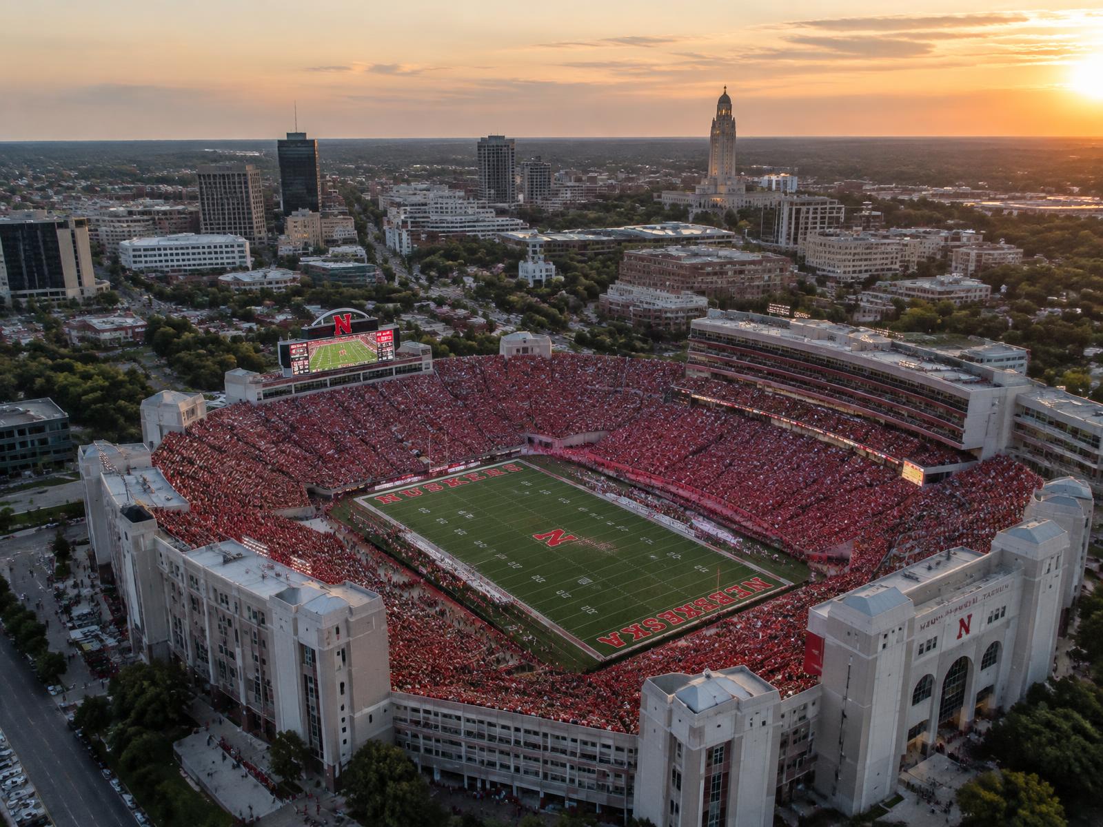 Aerial view of Memorial Stadium on game day with downtown Lincoln and the State Capitol behind it